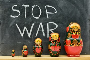 Grupo de muñecas matrioskas con fondo de una pizarra escrita con la frase stop war