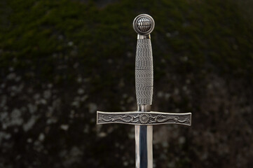 Medieval Sword with Mossy Rock Background
