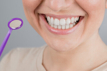 Caucasian woman with snow white smile holding dentist mirror.