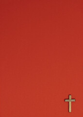 Image of a wooden cross on a red paper background. Flat lay, top view, minimal concept.