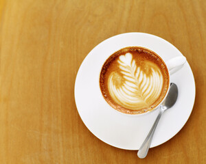 Made by an skilled barista. High angle shot of an artistically prepared cup of cappuccino sitting on a cafe table.