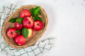 Happy red apples in a sweet basket on a white table. Art style, the top view has space for your messages.