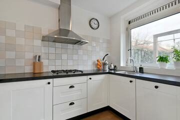 White furniture in the kitchen with black countertops and a new gas stove with extractor