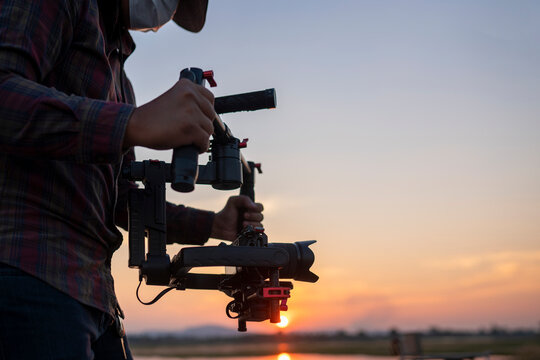 Filmmaker or content creator using stabilizer gimbal camera take video footage on the location outdoor
