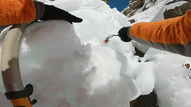 Man climbing ice waterfall with rope and ice axe