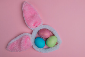 bunny ears on a pink background and three easter eggs