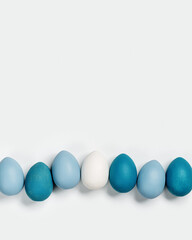 Painted Easter eggs blue, gray colored in row on white background with copy space. Chicken egg natural pastel shades. Easter holiday food, minimal design aesthetic flat lay