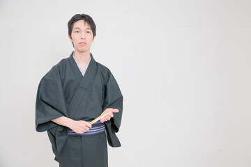Obraz na płótnie Canvas 扇子を持って手に当てる着物を着た日本人男性
