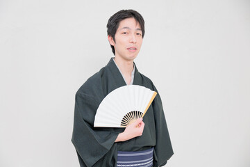 開いた扇子を持つ着物を着た日本人男性