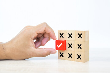 Hand choose check mark on cube wooden toy block stack with cross symbol for true or false changing mindset or way of adapting to change leader and transform quiz answer and poll concept