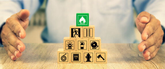Cube wooden toy block stack in pyramid with hand protect with fire icon and door exit sing or fire...