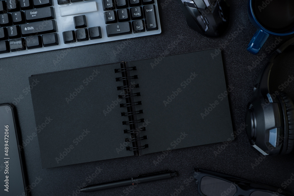 Poster top view working desk with keyboard headphone and open notebook on black table background