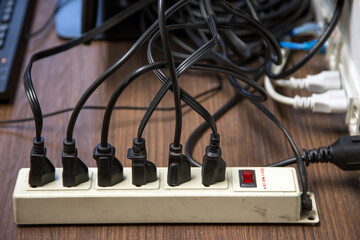 Old and damaged electric adapter power plug has many appliances are plugged outlet socket concept...