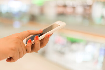 Woman hands buying online with a smart phone in the street in front a store