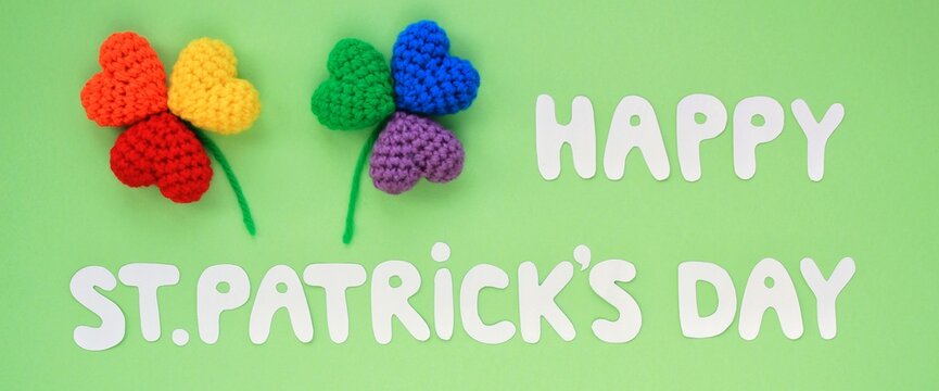 Happy St. Patrick's Day banner lettering and rainbow lgbt shamrock leaves on green background. Flatlay festive concept