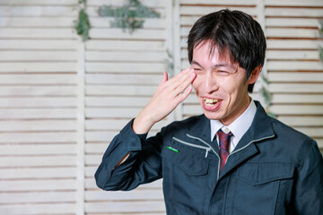 スーツに作業着を着た男が泣く