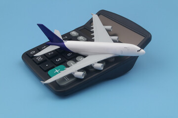 Airplane tickets cost concept. Airplane on black calculator on blue background.