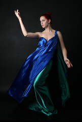  Full length portrait of pretty female model wearing  grecian goddess  toga gown, posing with elegant gestural movements on a studio background.