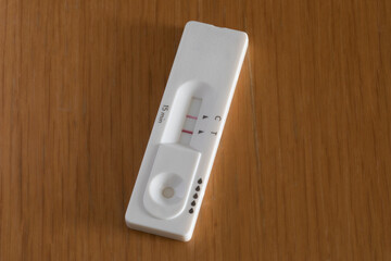 Covid rapid antigen test showing positive result on wooden table. Horizontal format.