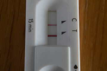 Covid rapid antigen test showing positive result on wooden table. Horizontal format close up with...