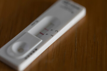 Covid rapid antigen test showing positive result on wooden table. Horizontal format with selective focus.
