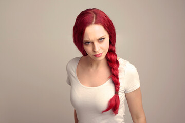 close up portrait of pretty female model with red hair in a braid, expressing emotion over the top facial expression on a studio background.