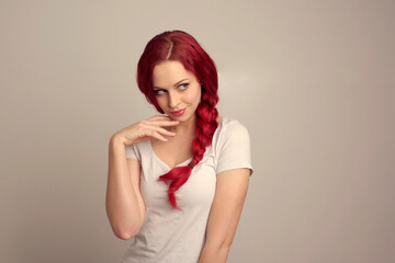 close up portrait of pretty female model with red hair in a braid, expressing emotion over the top facial expression on a studio background.