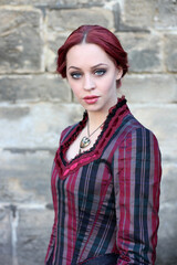 Full length portrait of red-haired woman wearing a historical victorian gown costume, walking around beautiful location with  Gothic stone architecture.