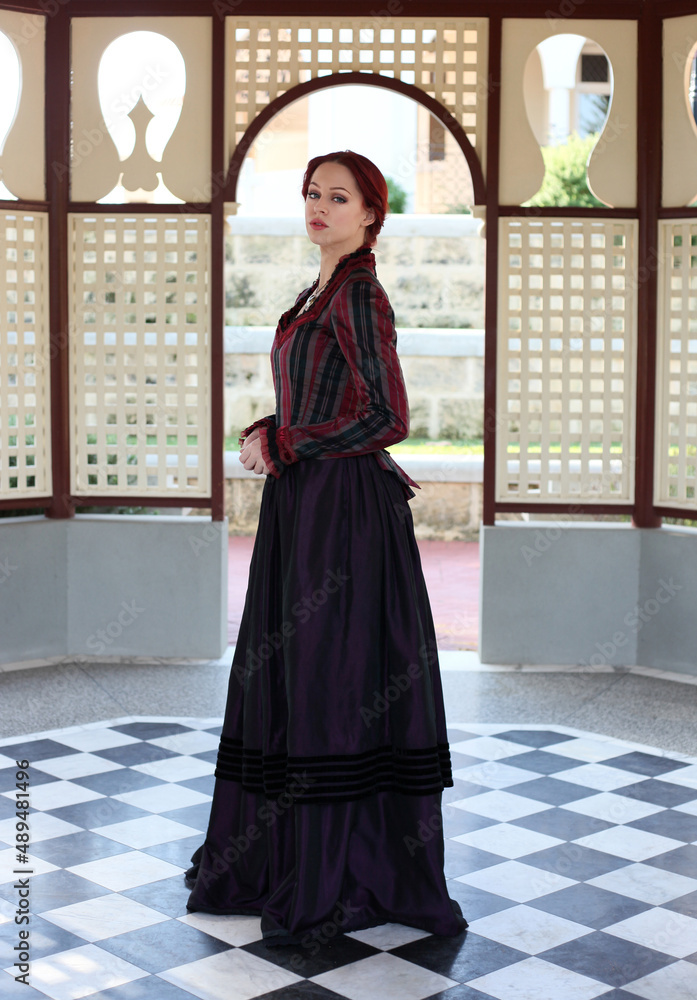 Canvas Prints Full length portrait of red-haired woman wearing a historical victorian gown costume, walking around beautiful location with  Gothic stone architecture.