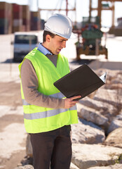 Fototapeta premium Successful engineer. Shot of a handsome young construction worker reading through the building plans.