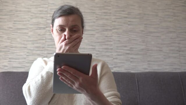 Worried, feared lady looking and reading shocking, bad, politic news. Internet online media on pad. Woman using tablet electronic device, scrolling at home apartment.