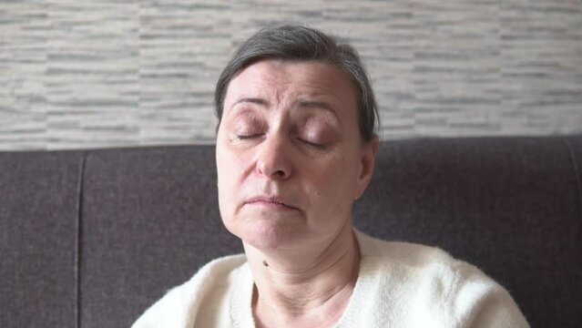 Sad, thoughtful, single woman sighing. Upset, pensive face looking in a camera thinking of problems, sitting alone. Senior lady feeling depressed, bad mood, negative thoughts and emotions.