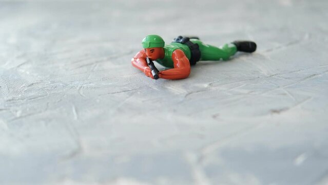 A toy soldier in camouflage and a helmet with a rifle in his hands crawls. War, defense.