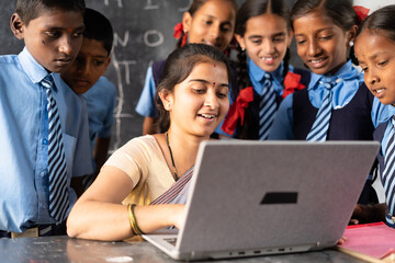 Young indian teacher teaching on laptop with school uniform students at classroom - concept of...
