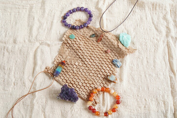 Fototapeta na wymiar Backdrop or Flat lay background of many raw stone and crystal, Is Amethyst, Amazonite, kyanite, 7 chakra pendant and incense, placed on linen cloth and brown paper with copy space in morning light.