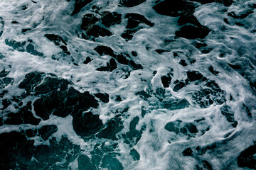 Top view of the ocean waves. Abstract blue ocean water with white foam background. Sea waves texture. Selective focus.