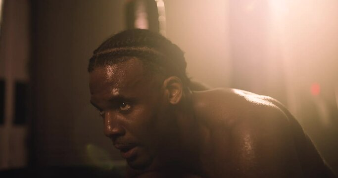 An African American Athlete Rests After An Intense Training Session. Shot In An MMA Boxing Gym With Low Key Lighting And A Scattering Of Haze. Captured On Red Digital Cinema Camera 