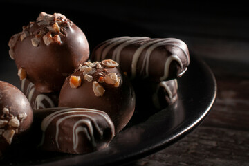 Chocolates on a dark plate in a black background, concept of sweet dessert food macro photography, horizontal