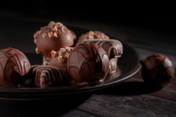 Chocolates on a dark plate in a black background, concep of sweet dessert food macro photography