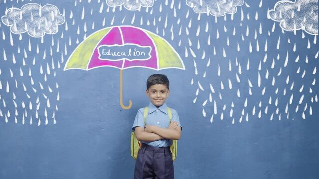 concept of security, growth and development from education showing by Happy smiling kid standing under rain with protection from umbrella with education on it.