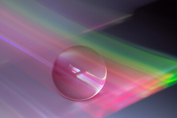 Glass ball and multicolored reflections on gray background