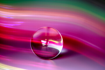 Glass ball and multicolored reflections on gray background