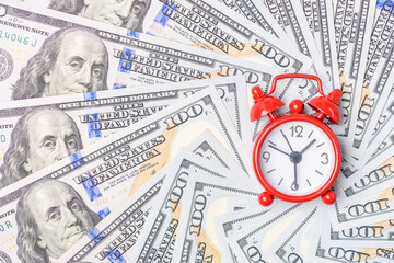 Time value of money concept : Red analog clock on US dollar banknote, depicting receiving money...