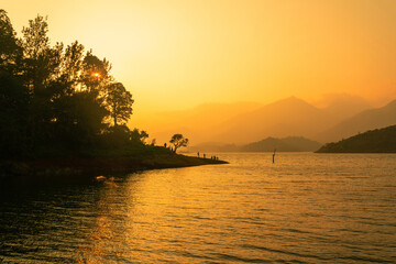 Fototapeta na wymiar Breath-taking view of the lake at sunset with magnificent trees in the background. beautiful click from Banasura Sagar Dam Wayanad selective focus image