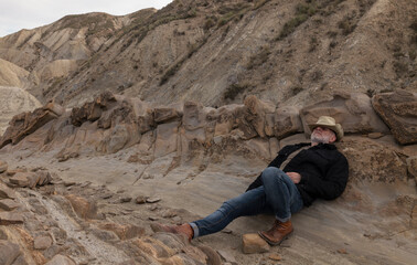 Portrait of adult man in cowboy hat sleeping on wild against rock. Almeria, Spain