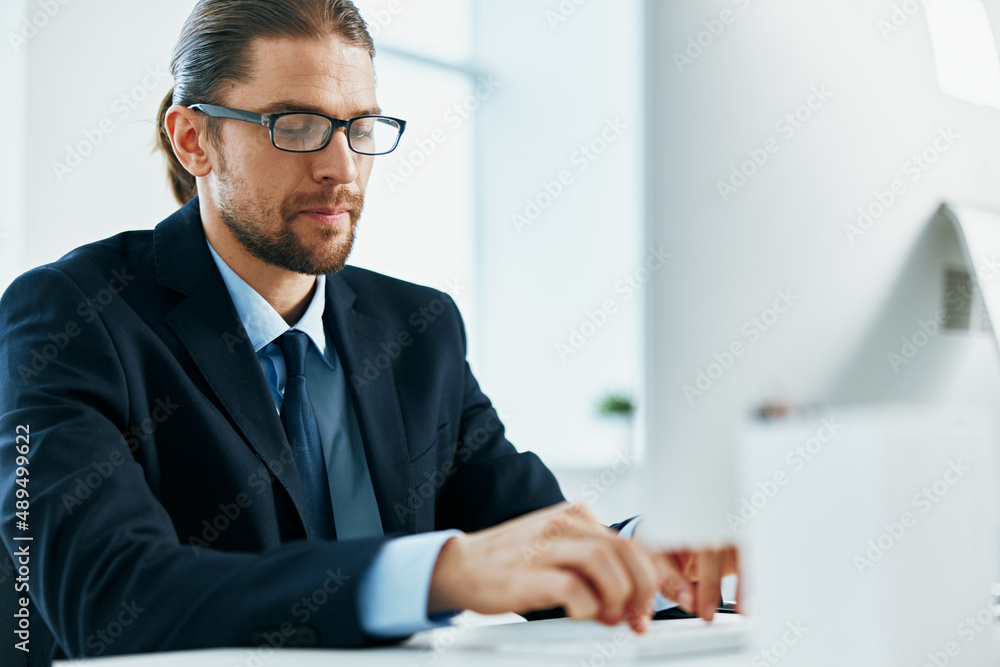 Wall mural business man in a suit sitting at his desk tired in front of a computer