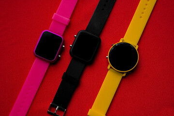 Female hand holding a red watch in a hole on a yellow background.