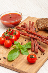 Thin smoked beer sausages on a wooden board with cherry tomatoes