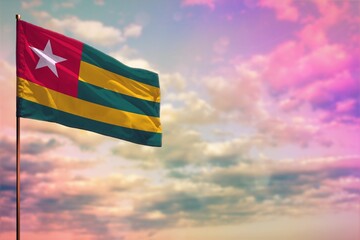 Fluttering Togo flag mockup with the space for your content on colorful cloudy sky background.