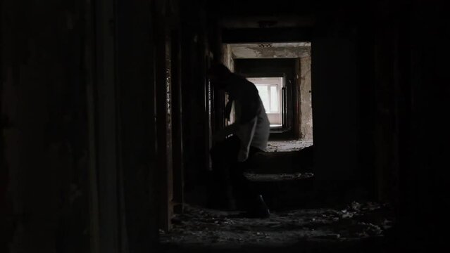  young man running in long corridor and entrances of an old abandoned building. Slow motion video. The concept of loneliness, labyrinths of fate, search for answers to questions